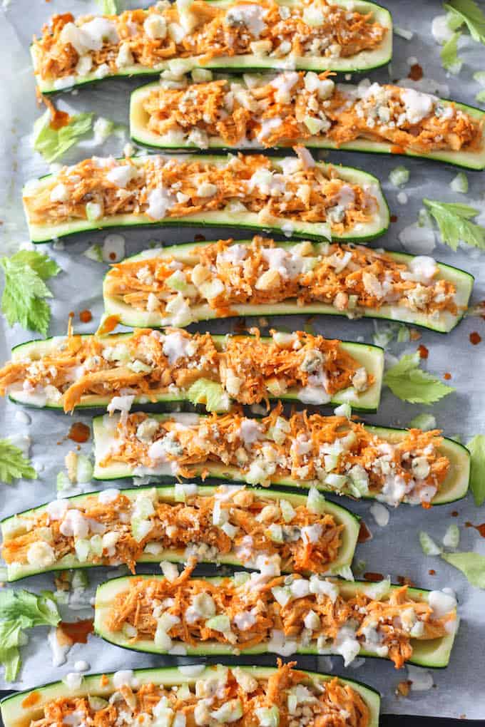 Buffalo Chicken Zucchini Boats | Destination Delish - A fun and healthy way to enjoy buffalo chicken! Tangy buffalo chicken stuffed inside a zucchini boats topped with crunchy celery, blue cheese, and ranch dressing