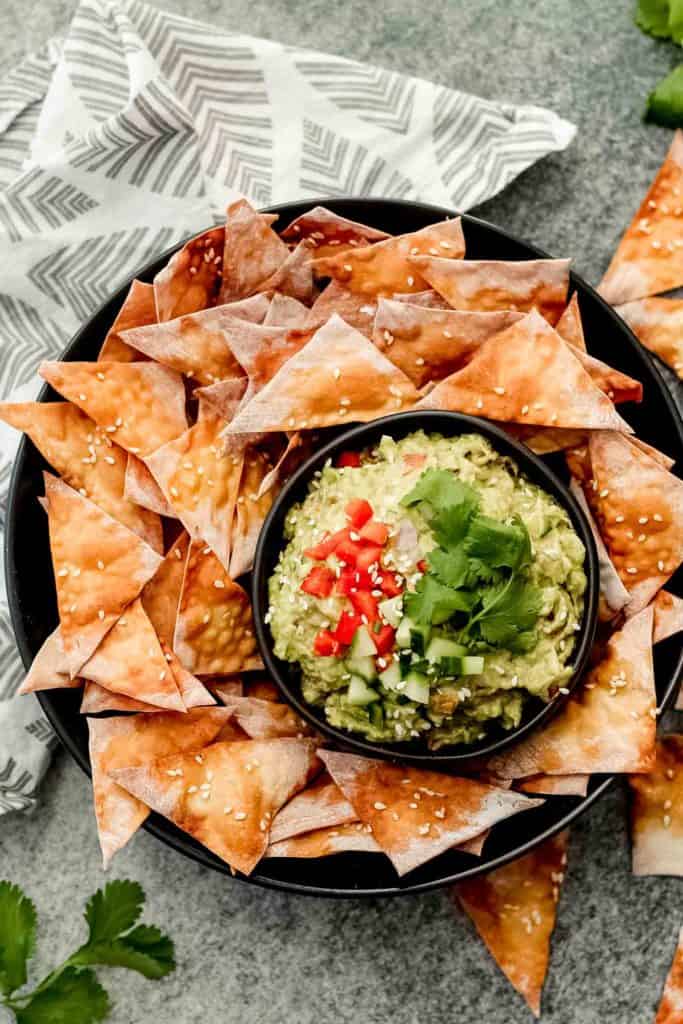 Guacamole in a bowl surrounded by wonton crisps