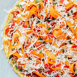 Thai Chicken Pizza with Cauliflower Crust | Destination Delish - Just in time for pizza night! A healthy, Thai inspired pizza with colorful, crunchy veggies, chicken, and a tangy peanut sauce atop cauliflower crust.