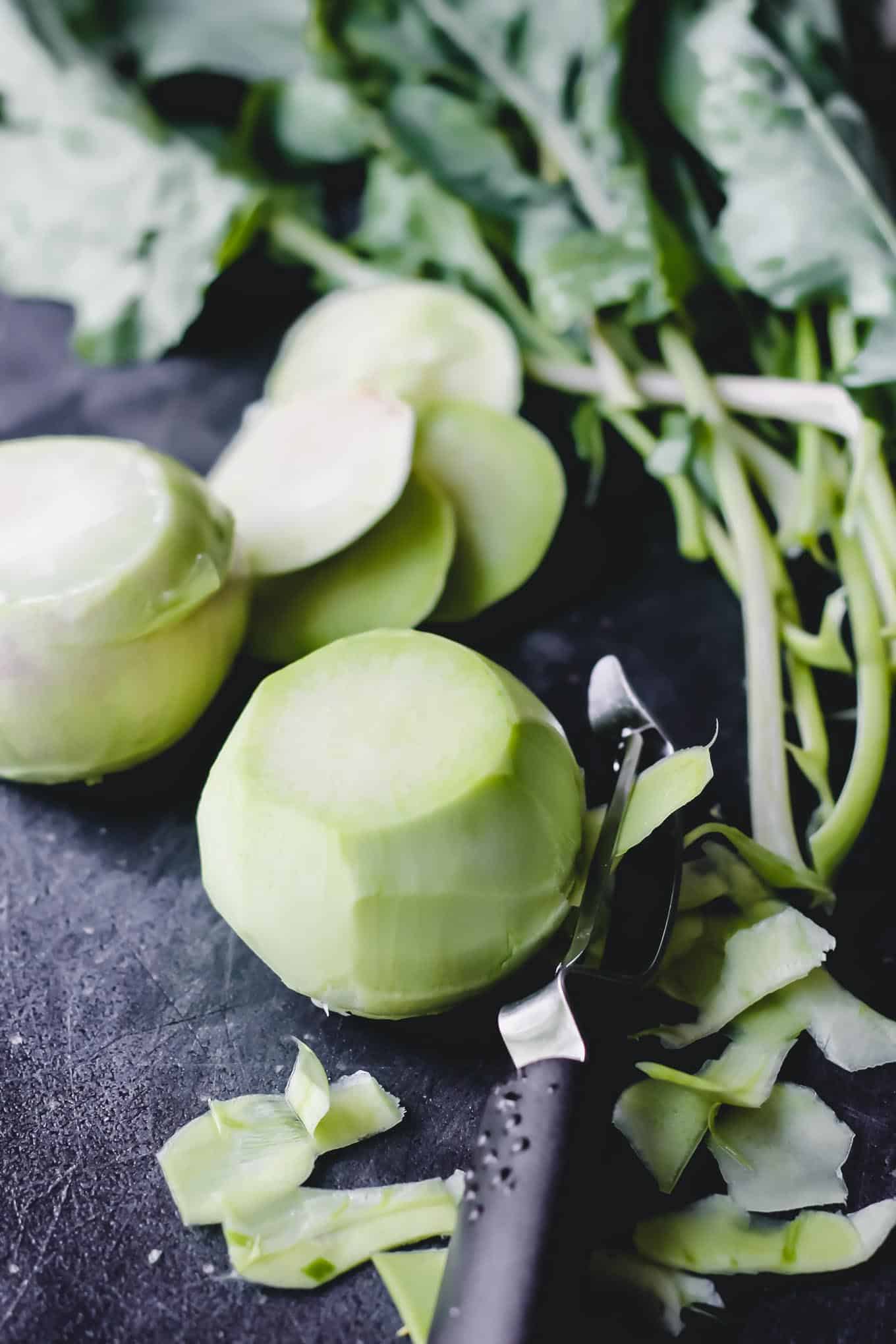 Using a vegetable peeler to remove outer layers of kohlrabi