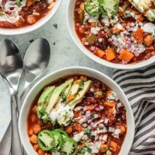 BBQ Sweet Potato Quinoa Chili in white bowls topped with garnishes.