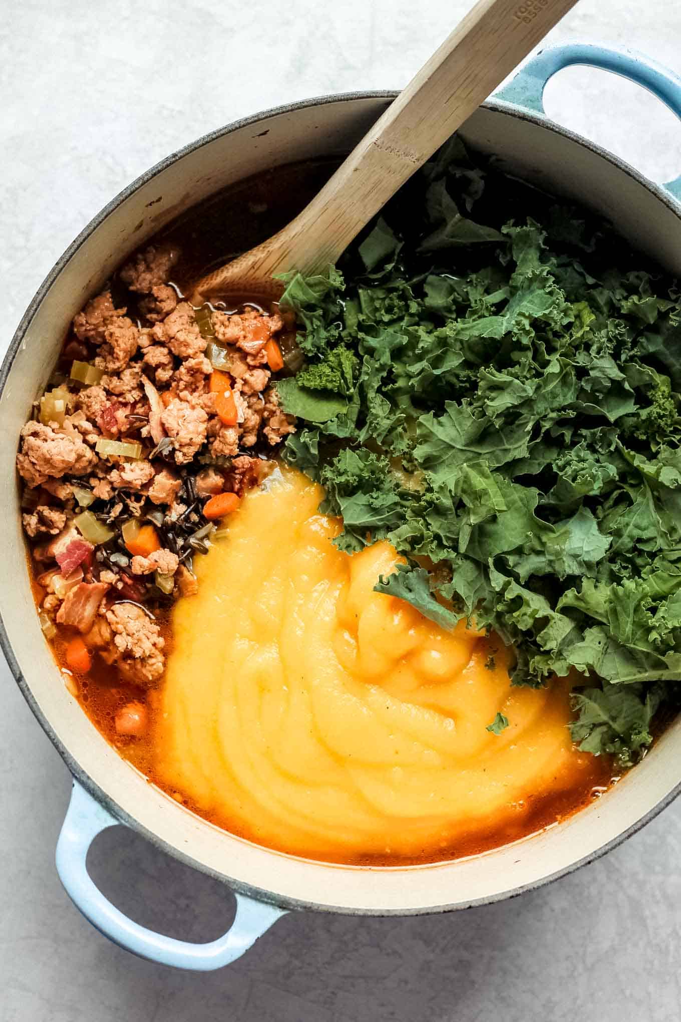 The wild rice and sausage mixture, kale, and pureed butternut squash in the pot prior to mixing together.