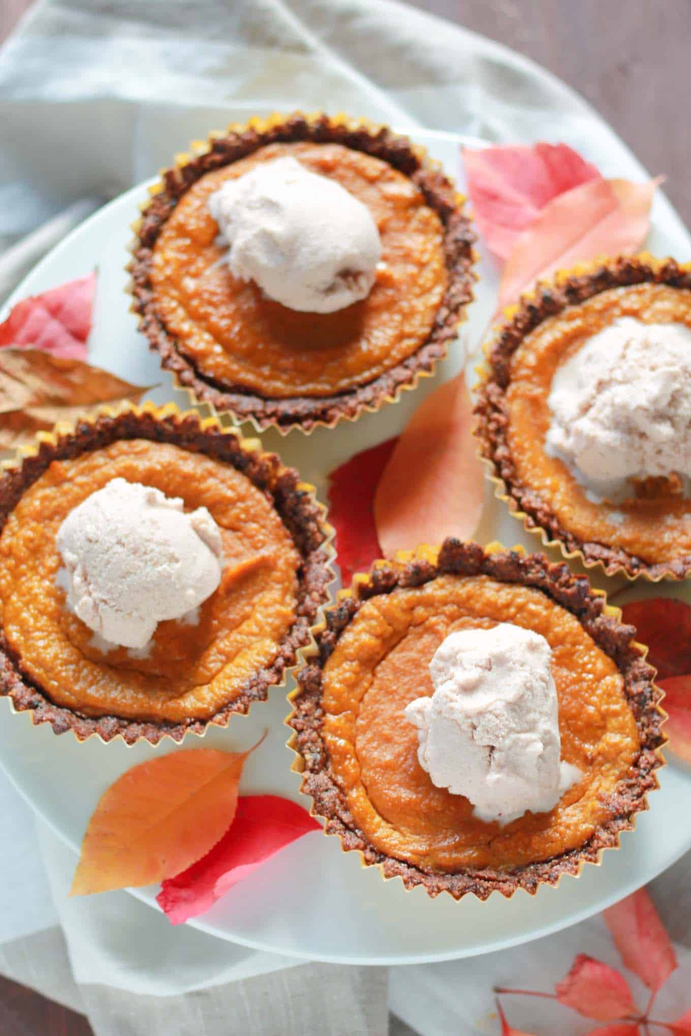 Four mini pies on a cake stand with fall leaves surrounding them